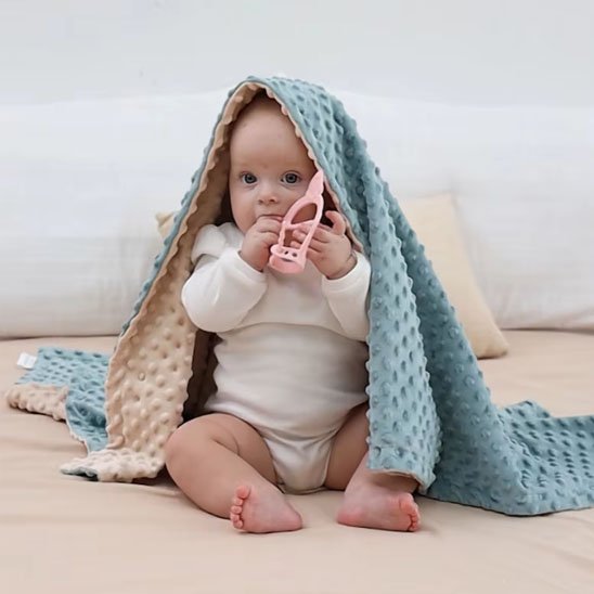 Bébé assis avec couverture bébé bleu et crème 