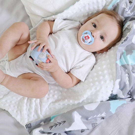Bébé avec sucette sur couverture bébé grise