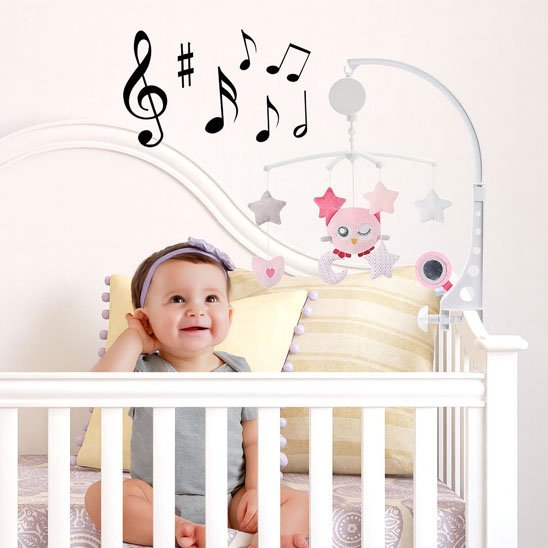 Bébé fille assit dans lit avec mobile musical 