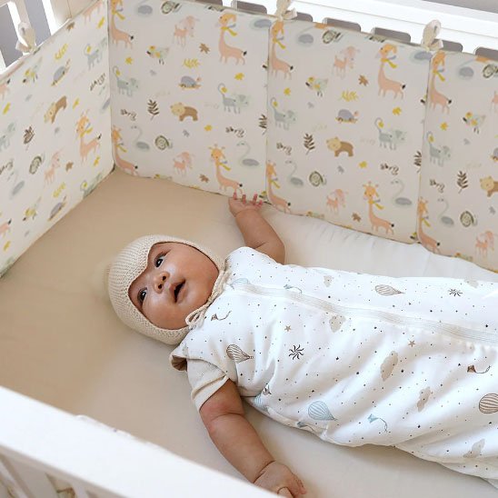 Bébé souriant dans lit avec tour de lit