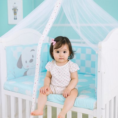 Enfant assis dans lit avec ciel de lit bébé